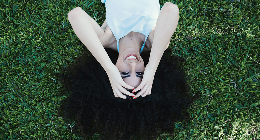 Woman with dark hair lying on grasss